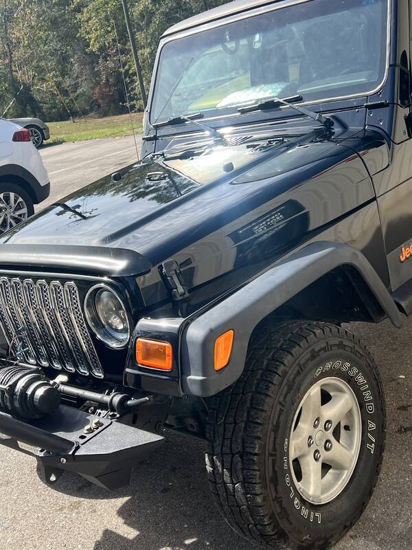 Front of a glossy black Jeep Wrangler showing the hood, grille and winch bumper